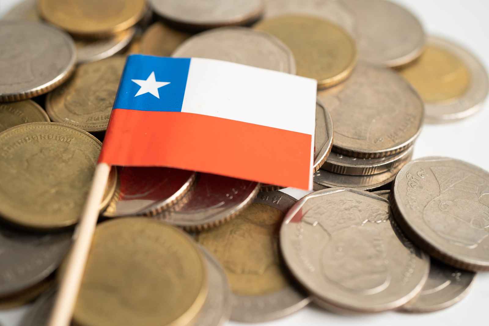 Bandera de Chile clavada sobre un montón de monedas
